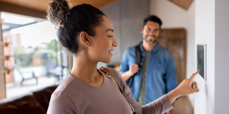 Happy Latin American couple leaving their house and setting the alarm using a home automated system